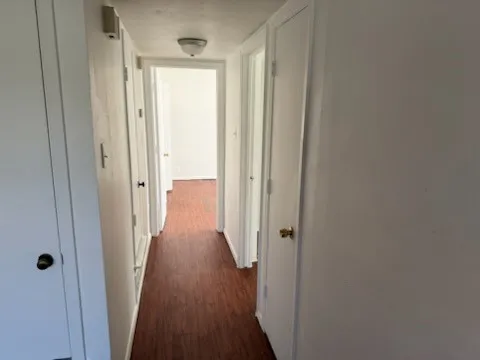 Hallway featuring dark wood-style floors and baseboards