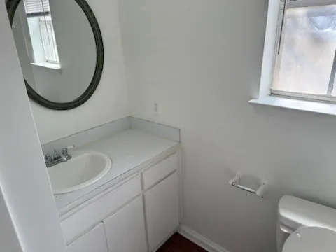 View of the sink in the bathroom with baseboards, toilet, vanity, and a healthy amount of sunlight
