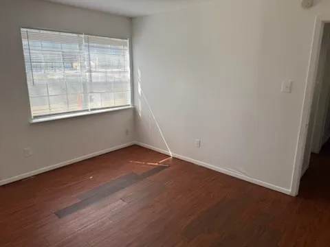 Another angle of the living room with baseboards and wood finished floors
