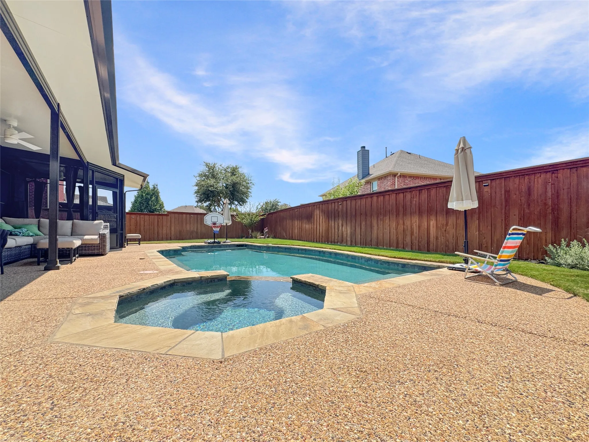 Expansive backyard featuring a built-in swimming pool with an integrated spa, a substantial covered patio, and a privacy fence