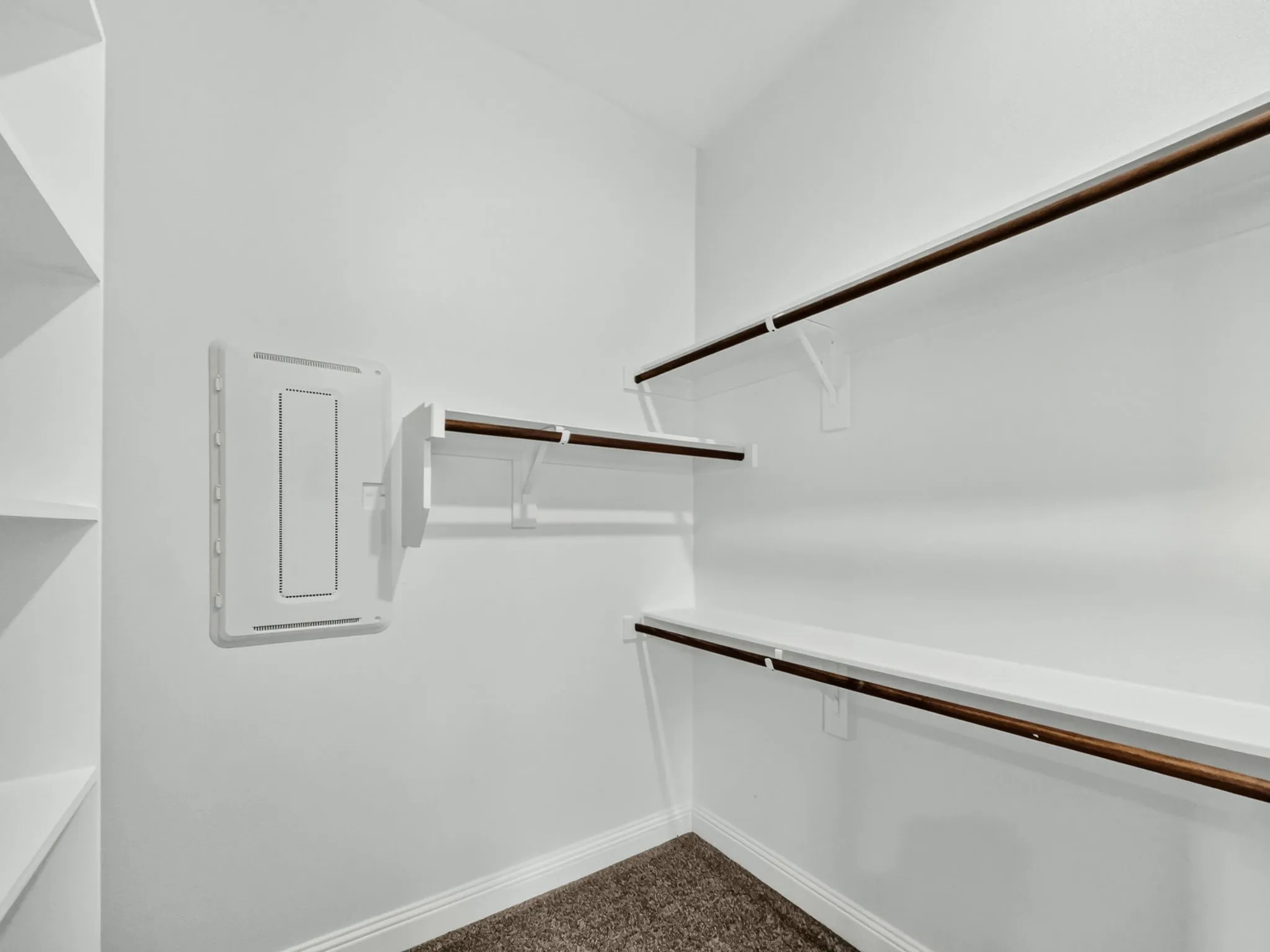 Built-in shelving, multiple hanging rods, and carpet flooring