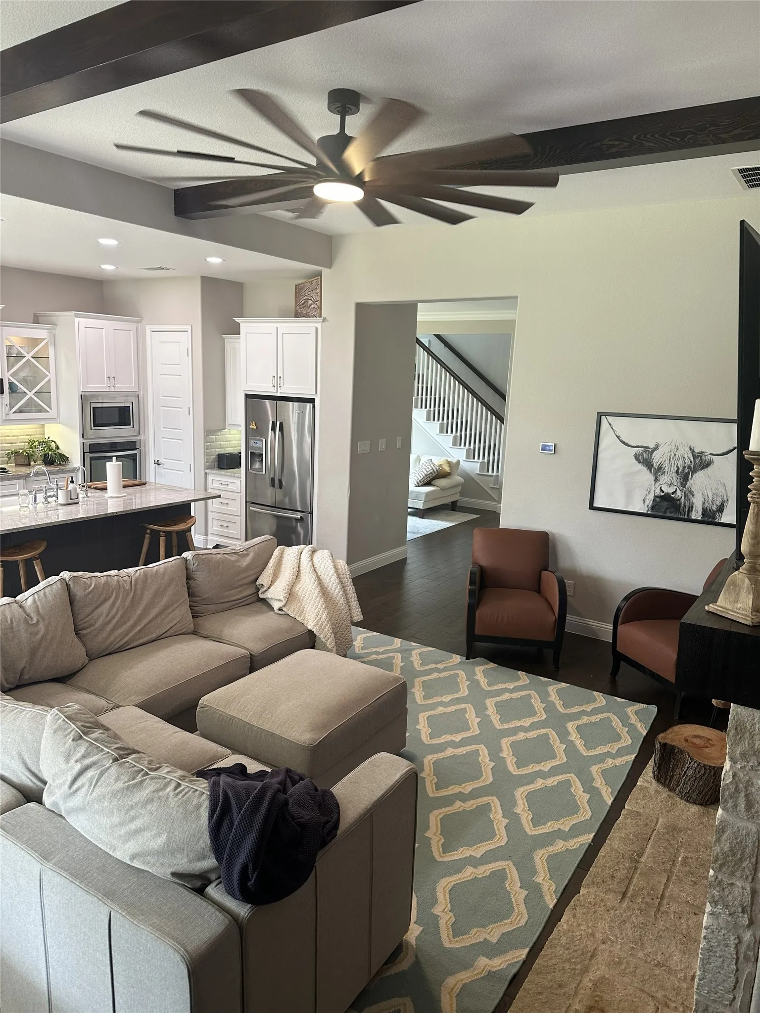 Exposed dark wood ceiling beams, recessed lighting, and a modern ceiling fan