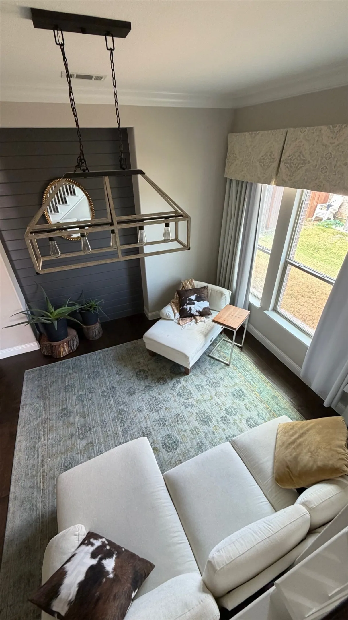 Hardwood-style flooring, a large window, and a linear chandelier fixture