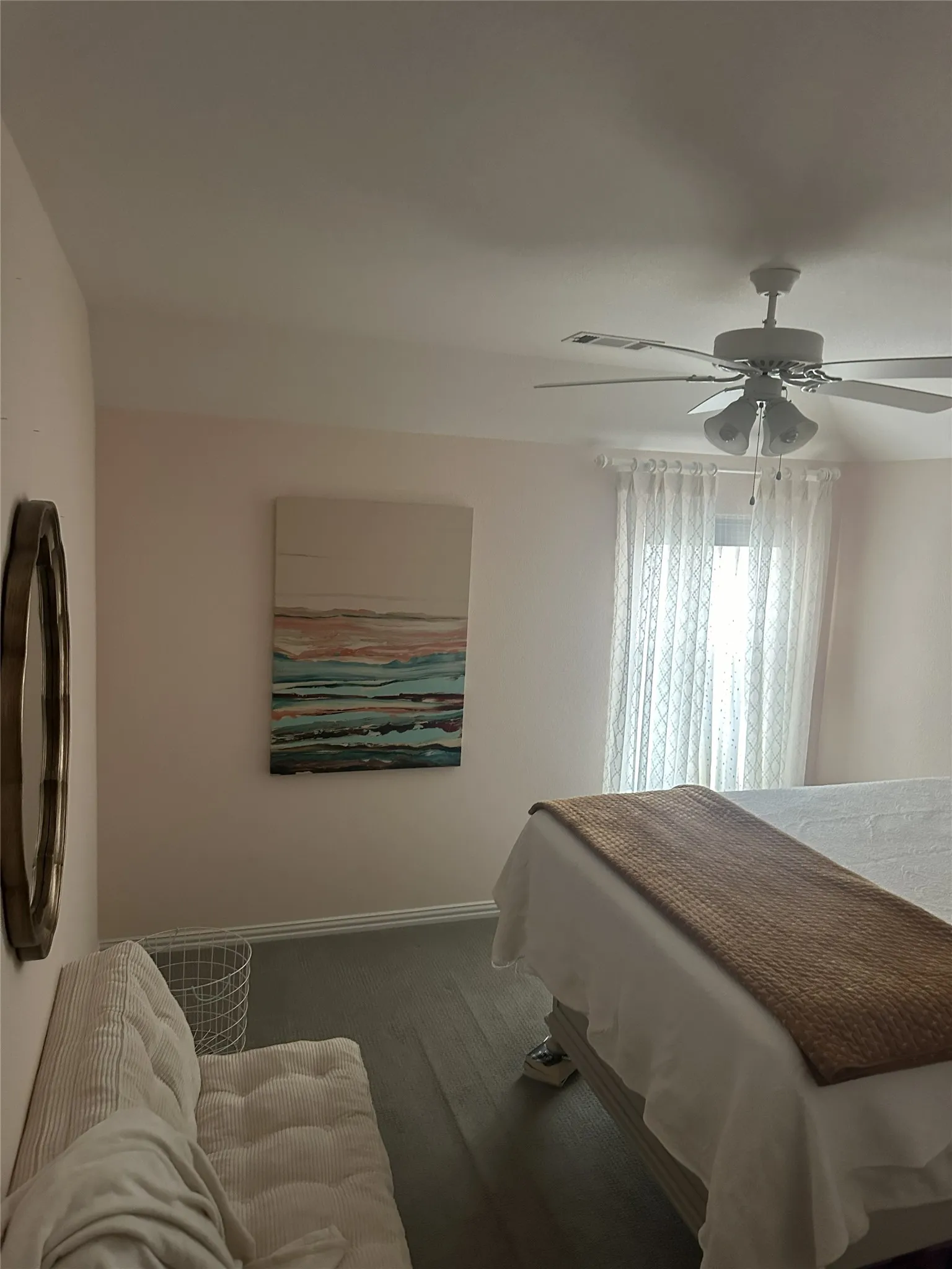 Vaulted ceiling with a ceiling fan light fixture, wood-finish flooring, and window with sheer curtains