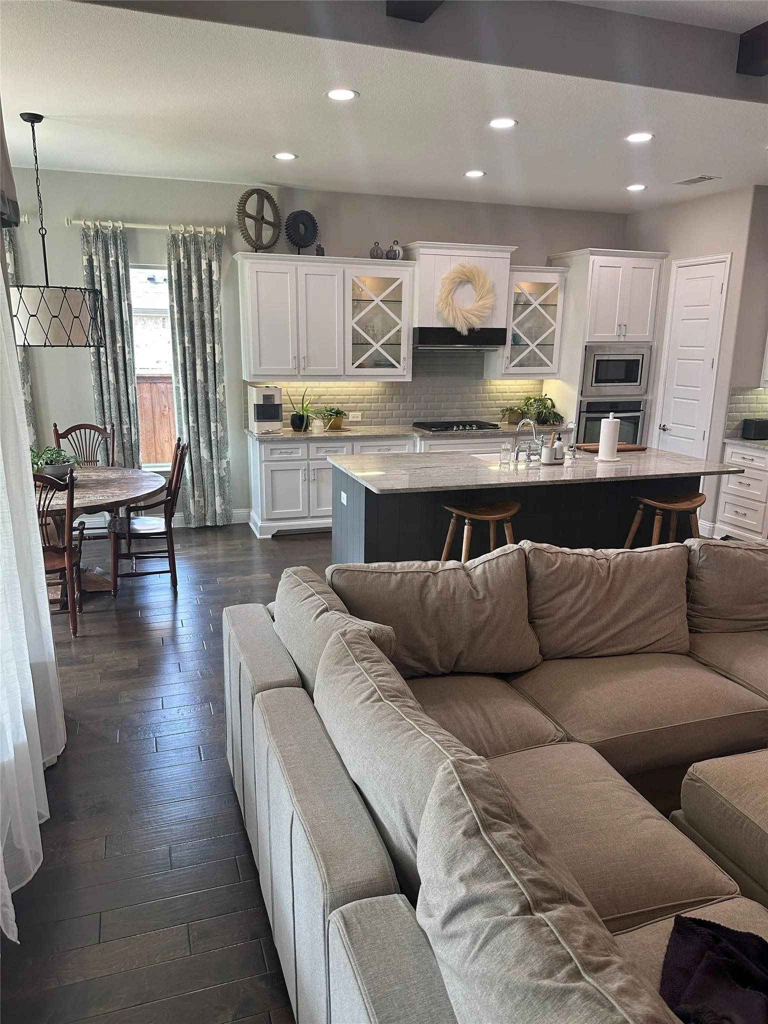 Gourmet kitchen with white cabinetry, built-in double oven, and a center island featuring a sink