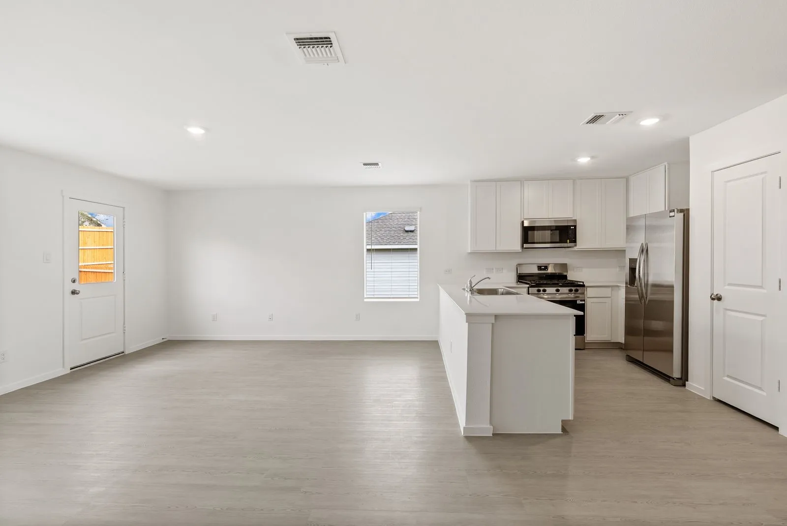 Open concept living space featuring wood-finish flooring, white walls, and recessed lighting