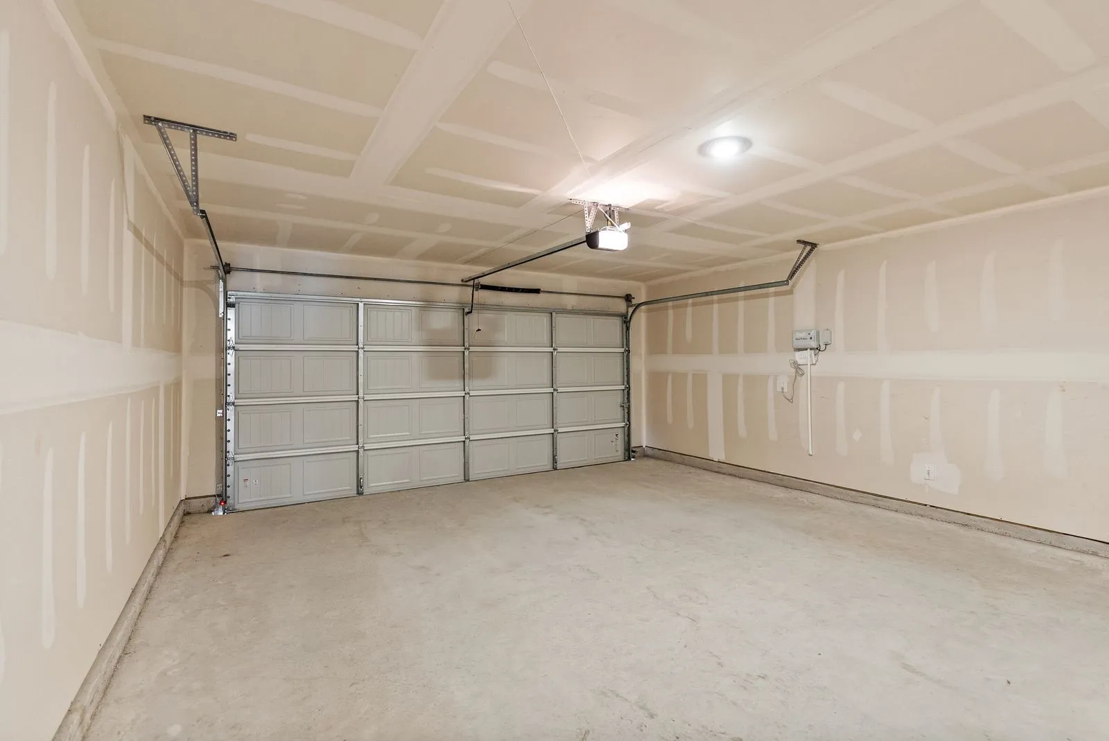 Concrete flooring, neutral wall tones, overhead lighting, garage door opener mechanism