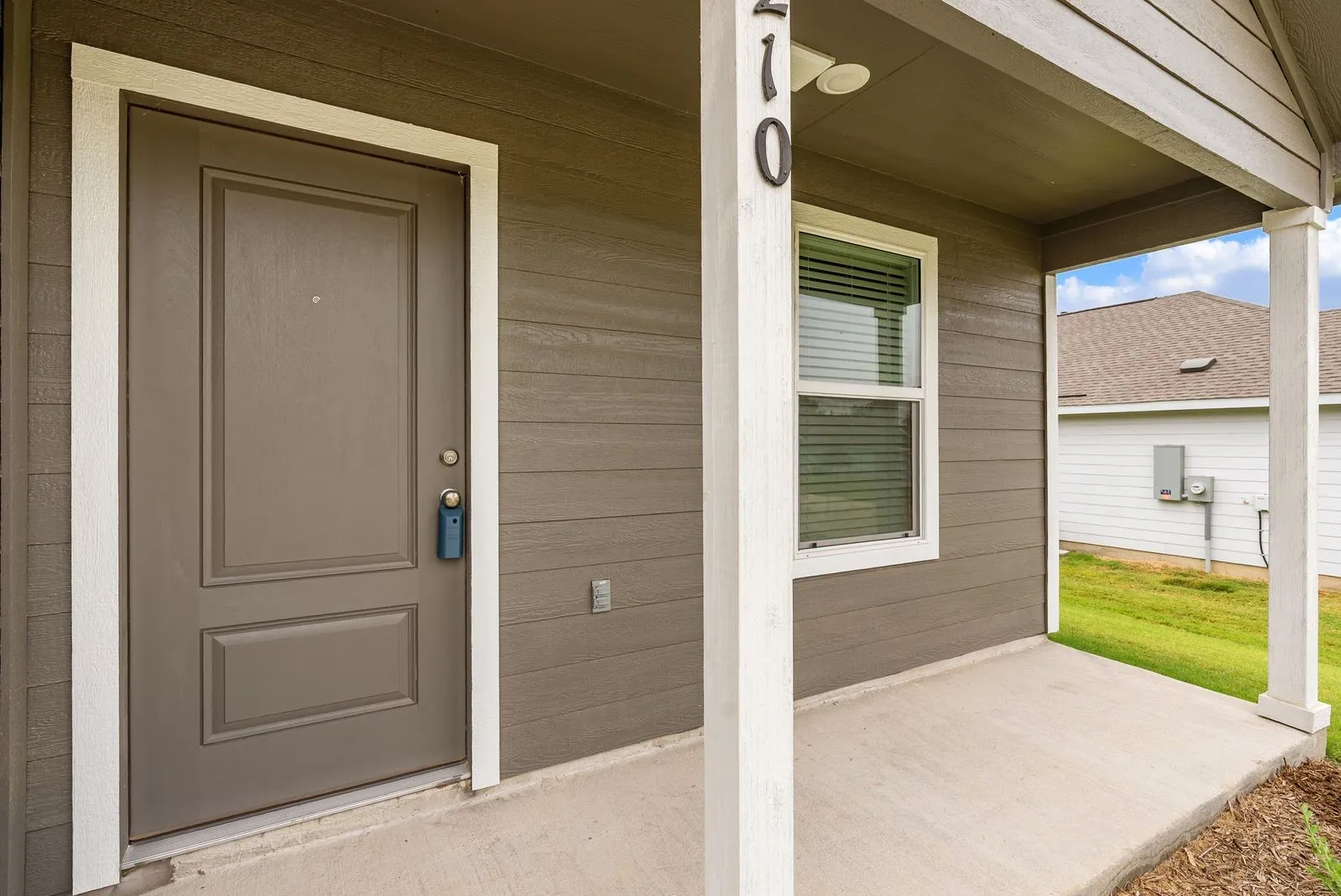 Covered front porch with concrete flooring and white support pillars