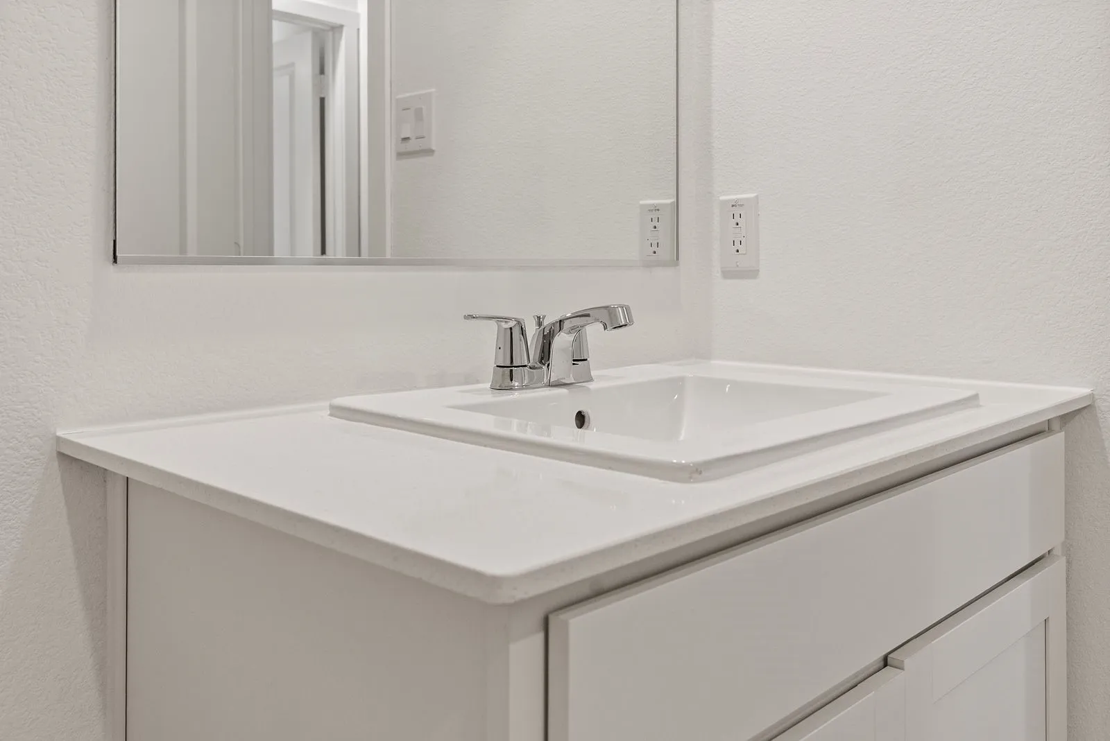 White vanity with integrated sink, chrome faucet, and expansive countertop