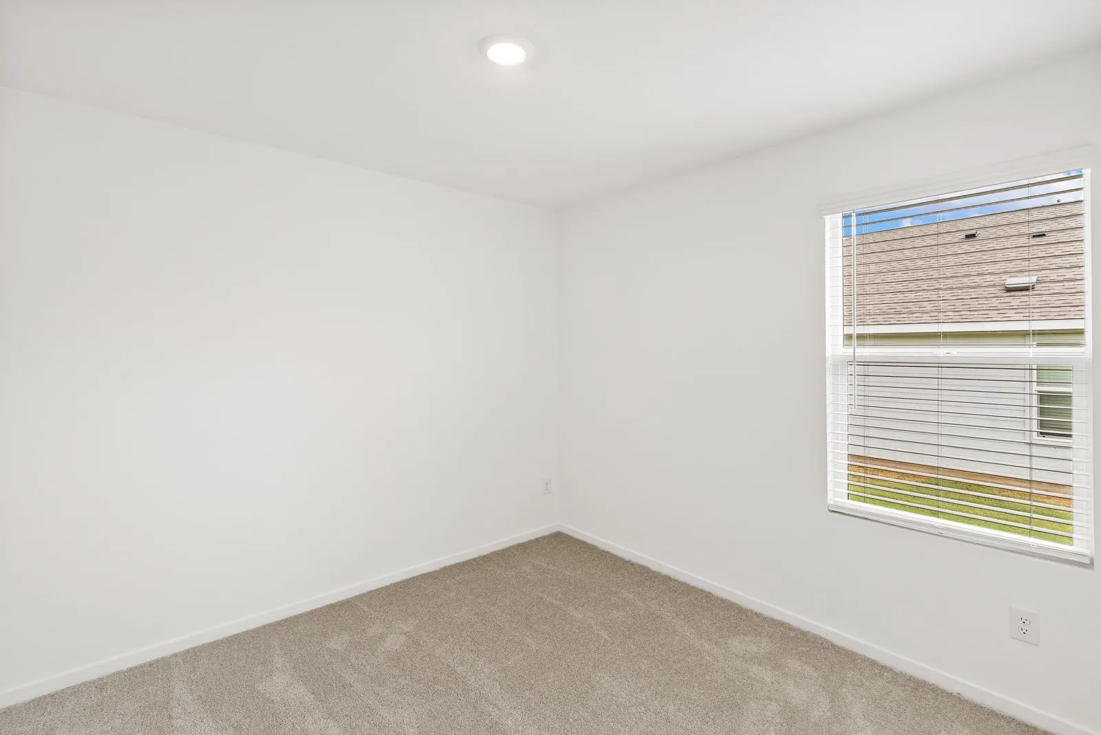 Recessed ceiling lighting, neutral tone carpeting, white walls, and a window with horizontal blinds