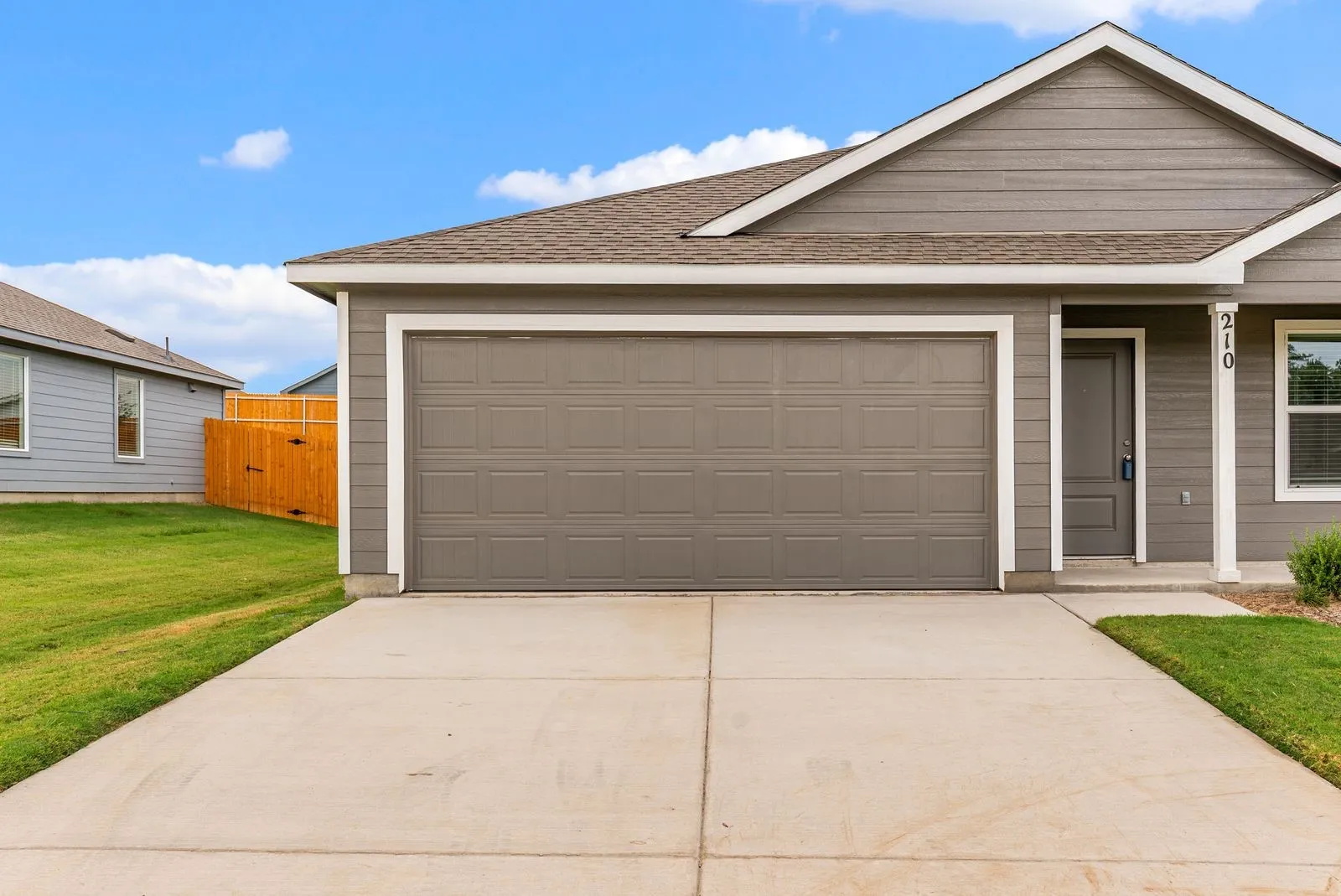 Gray siding exterior with white trim, two-car garage, concrete driveway, and front entry