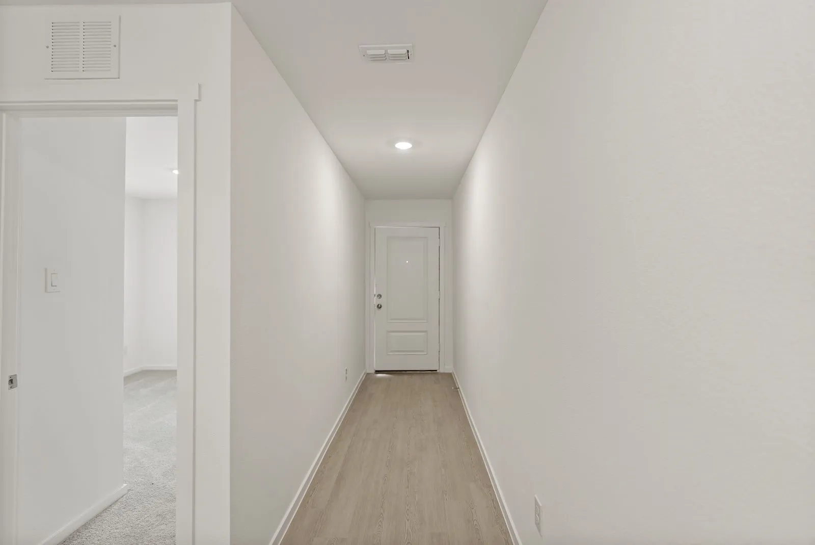 Recessed lighting illuminates the wood-finish flooring in this entry corridor