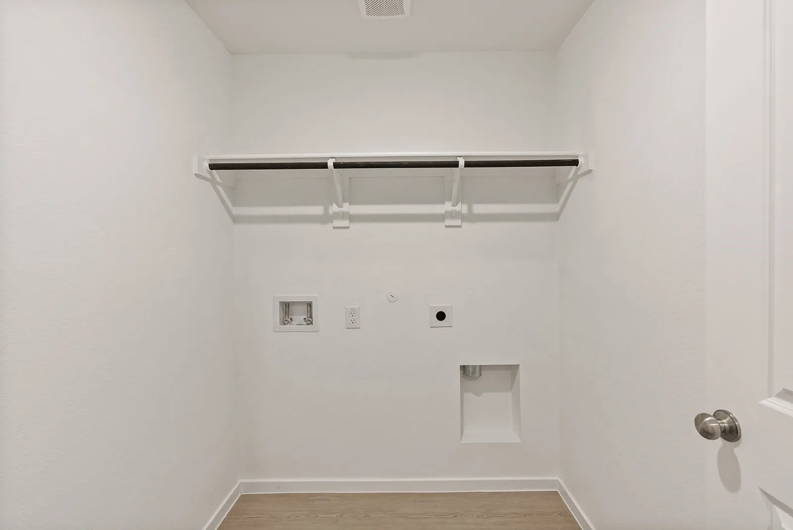 Utility space with wood-finish flooring, white walls, and an overhead storage rack