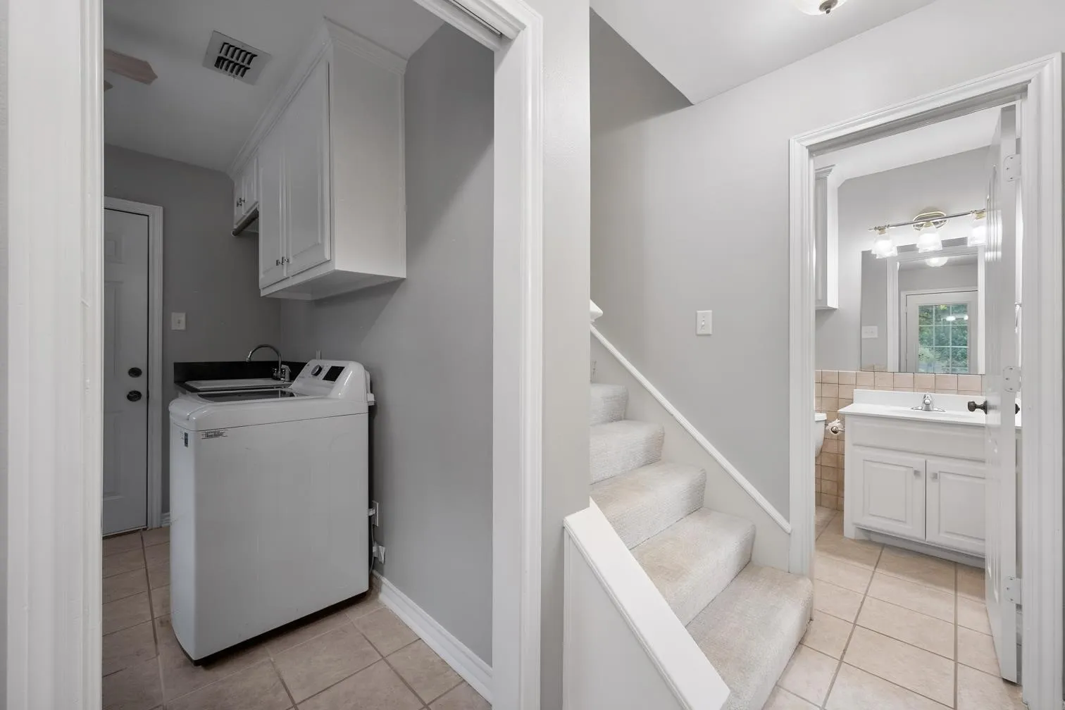 Utility area with integrated sink and upper cabinetry, complemented by a staircase to the game room with a full bathroom at the base of the stairs