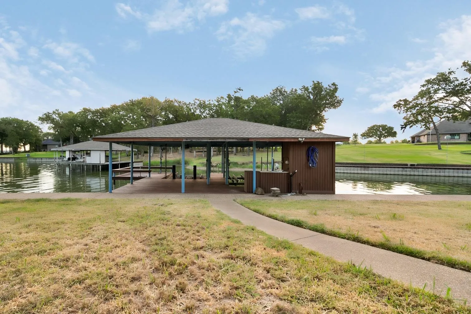 Covered boat dock with multiple slips, wood decking, and a built-in storage shed