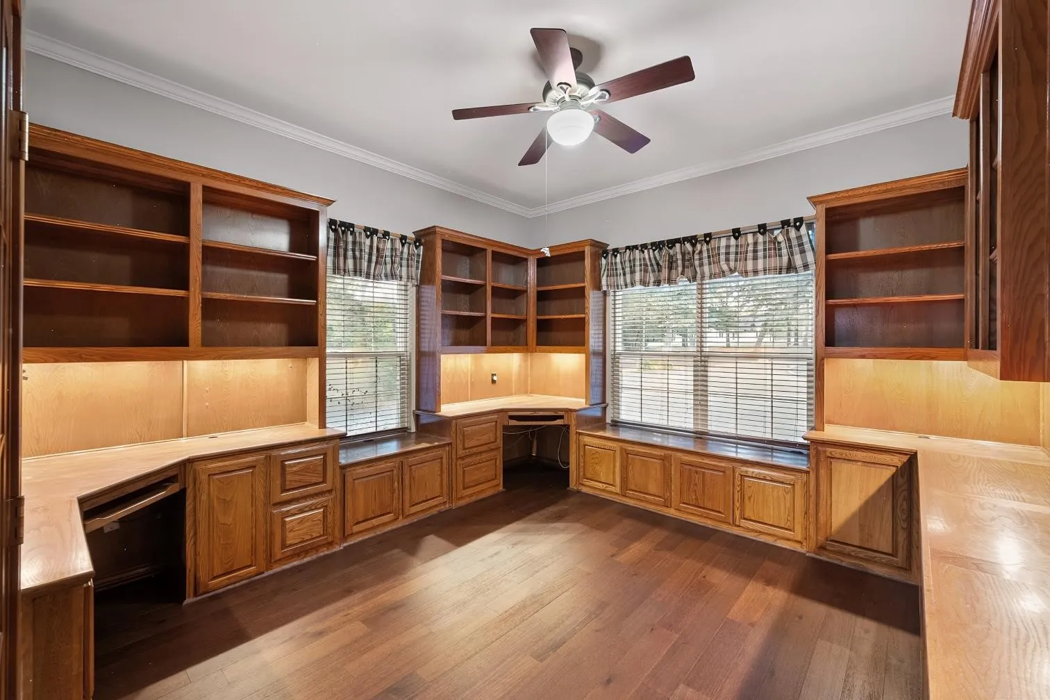 Engineered hard wood flooring, built-in wooden shelving, integrated wooden desks, multiple windows with blinds, and a ceiling fan
