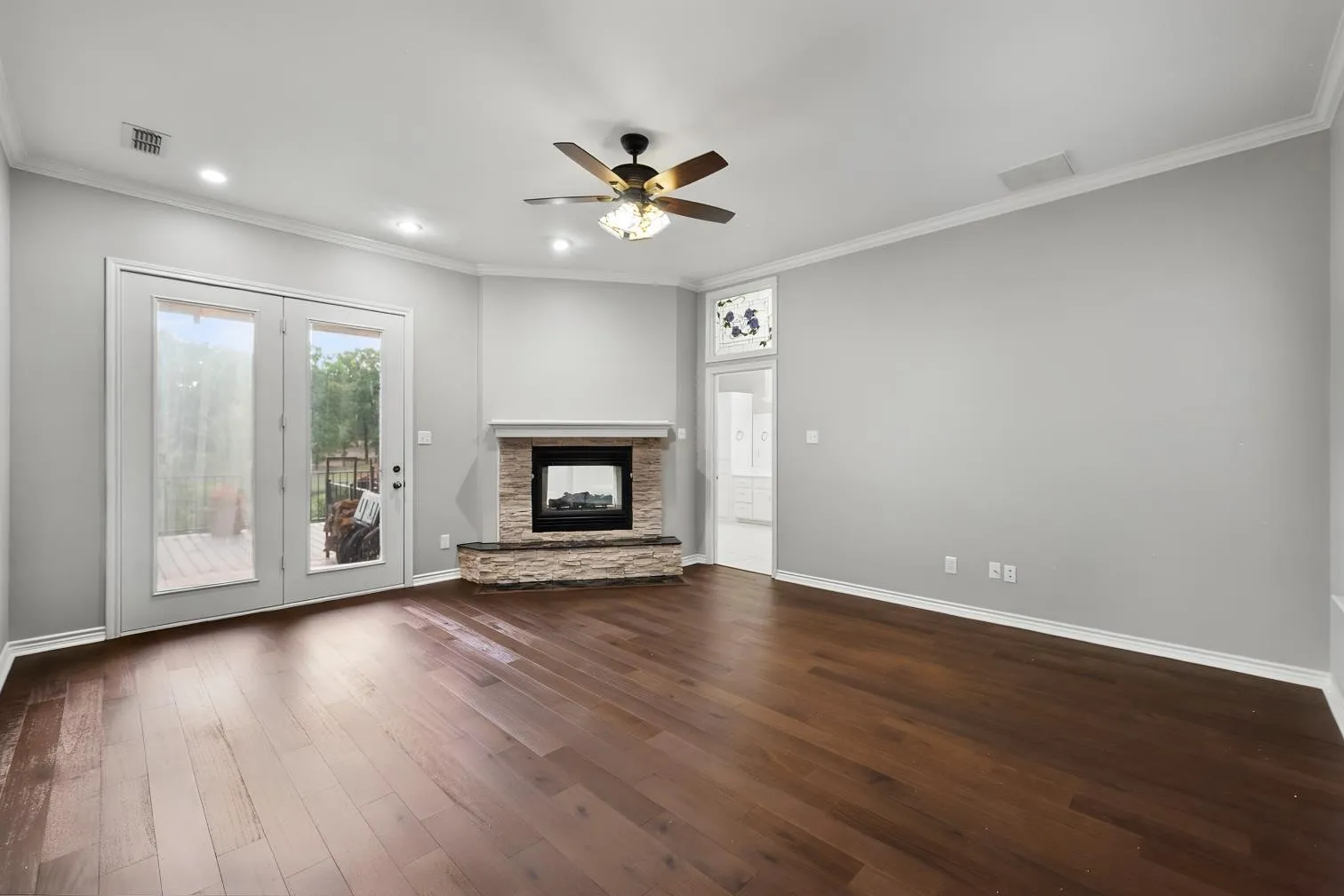 Engineered hard wood flooring, see through corner fireplace with stone surround, crown molding, double French doors, and recessed lighting