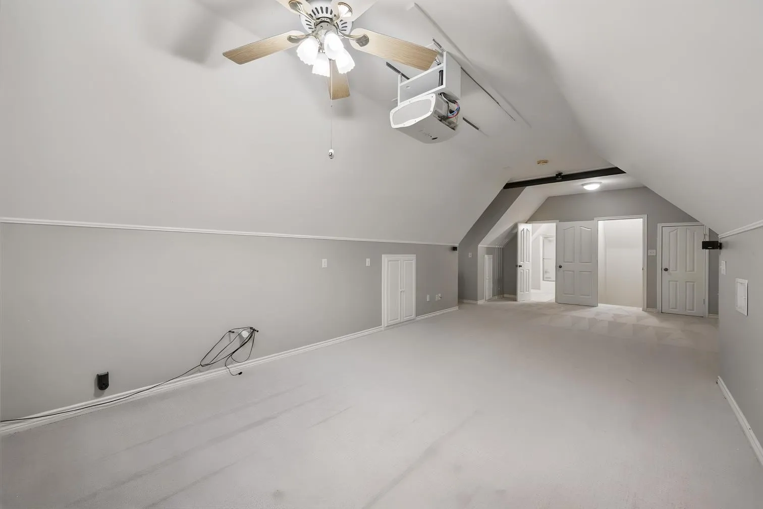 Carpeted room with sloped ceilings, and a movie projector and screen