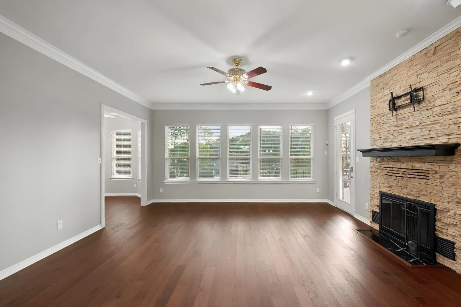 Engineered hardwood flooring throughout, stone-clad fireplace with mantel, recessed lighting, ceiling fan, and multiple windows with an amazing view of the lake
