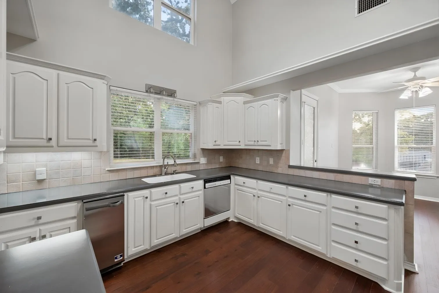 Kitchen with white cabinetry, dark countertops, a tile backsplash, and stainless steel appliances