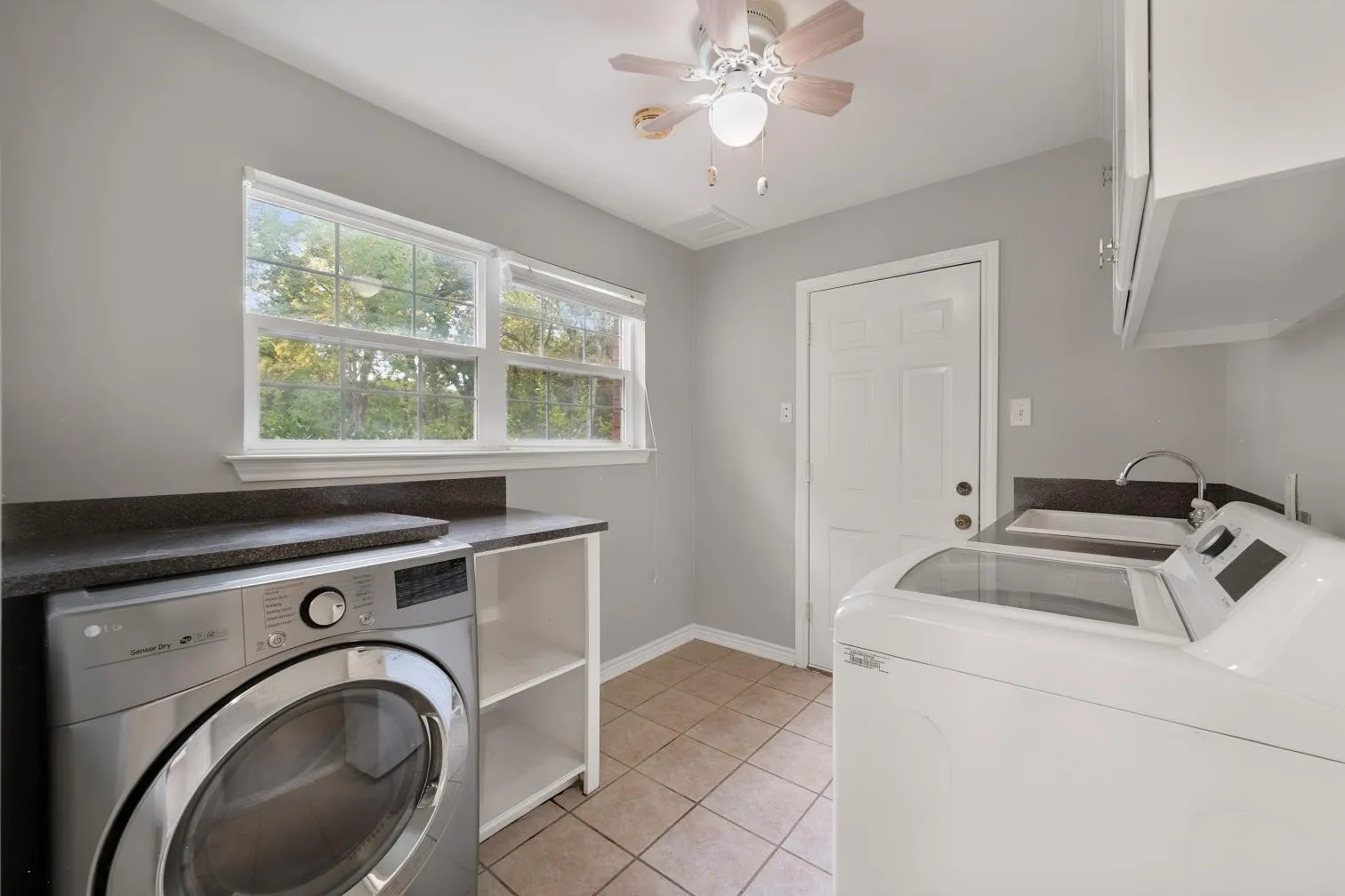 Utility room featuring a utility sink, tiled flooring, and built-in cabinetry