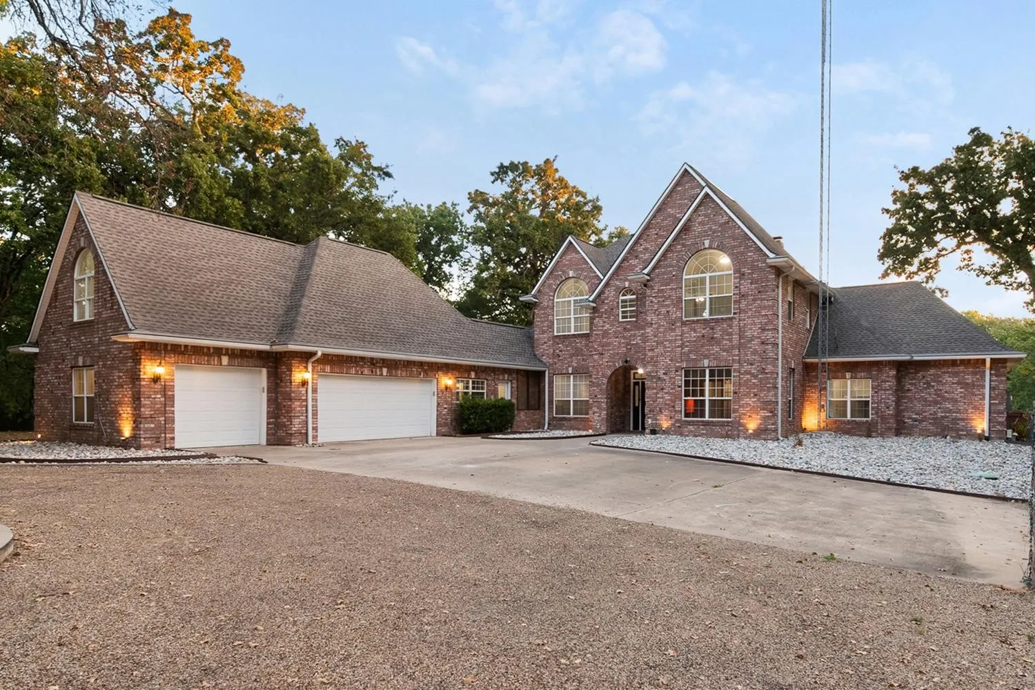Brick exterior with a multi-gabled roofline, arched entry, and integrated three-car garage