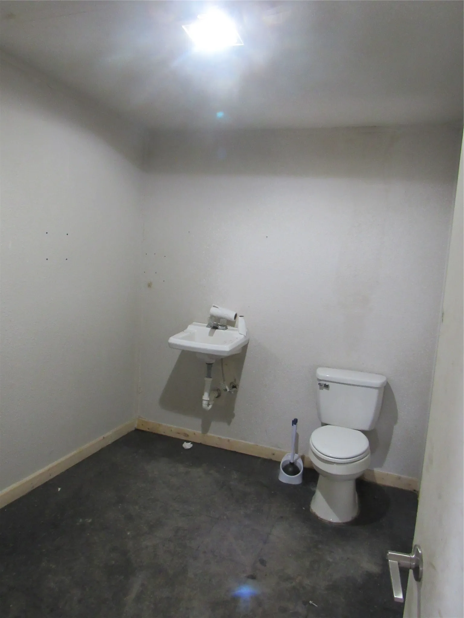 Compact bath space featuring a wall-mounted sink, a toilet, and a ceiling-mounted light fixture