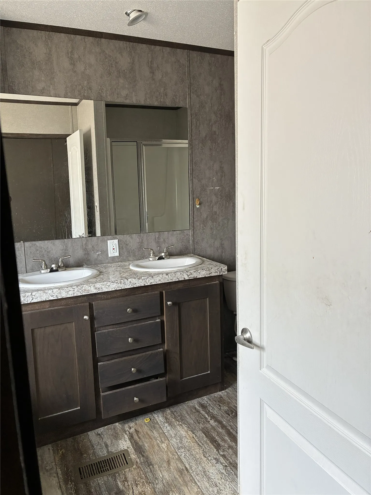 Double vanity with integrated sinks, wood-finish cabinetry, and a full-width mirror