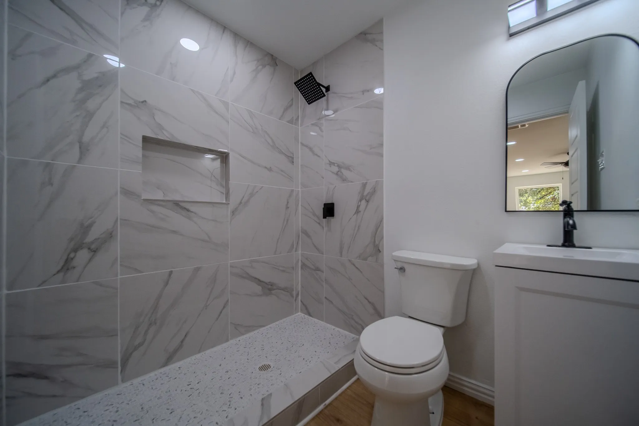 Walk-in shower with marble-look tile surround and recessed niche
