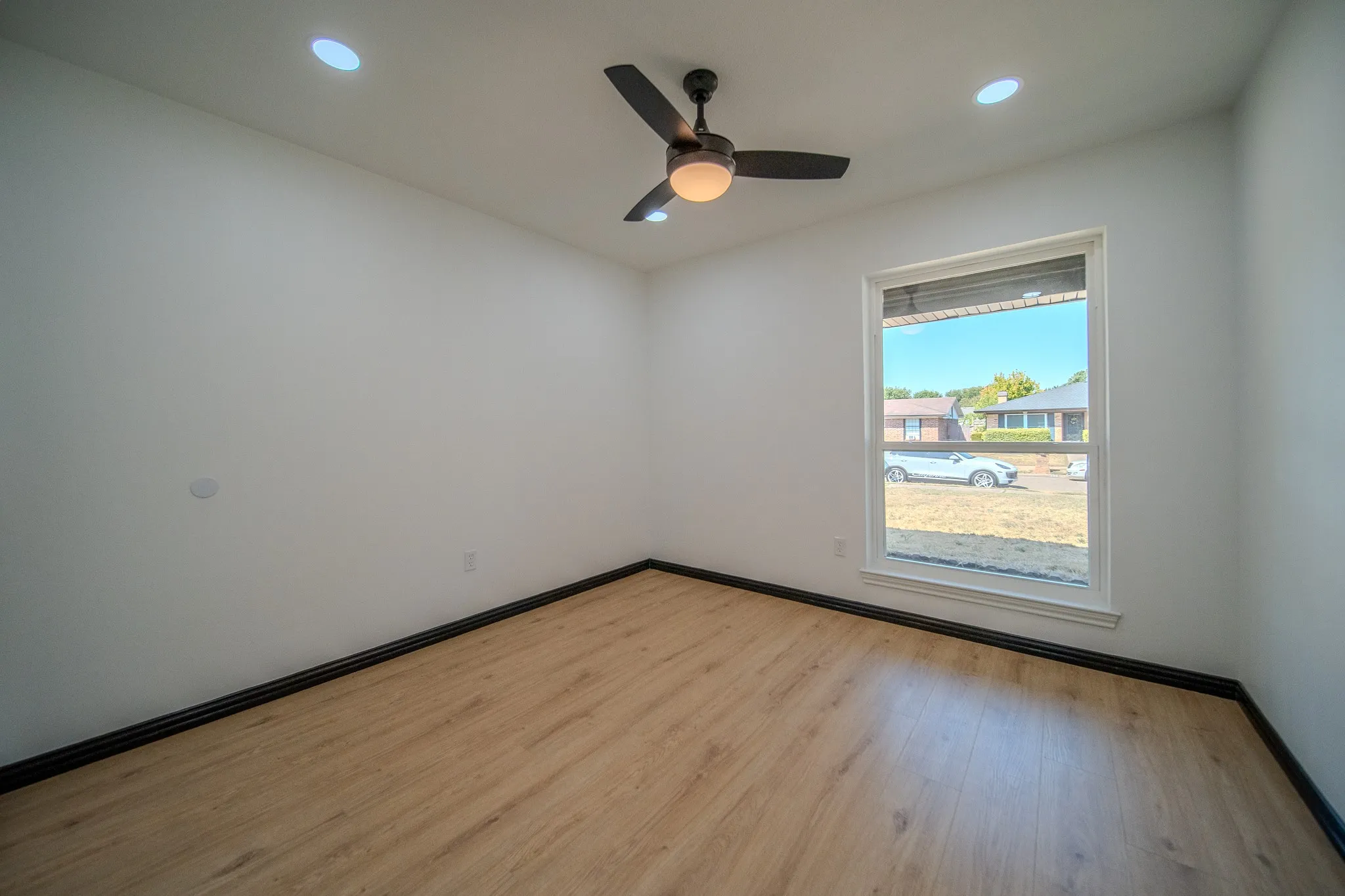 Recessed ceiling lighting, wood-finish flooring, white walls, and a ceiling fan with integrated light