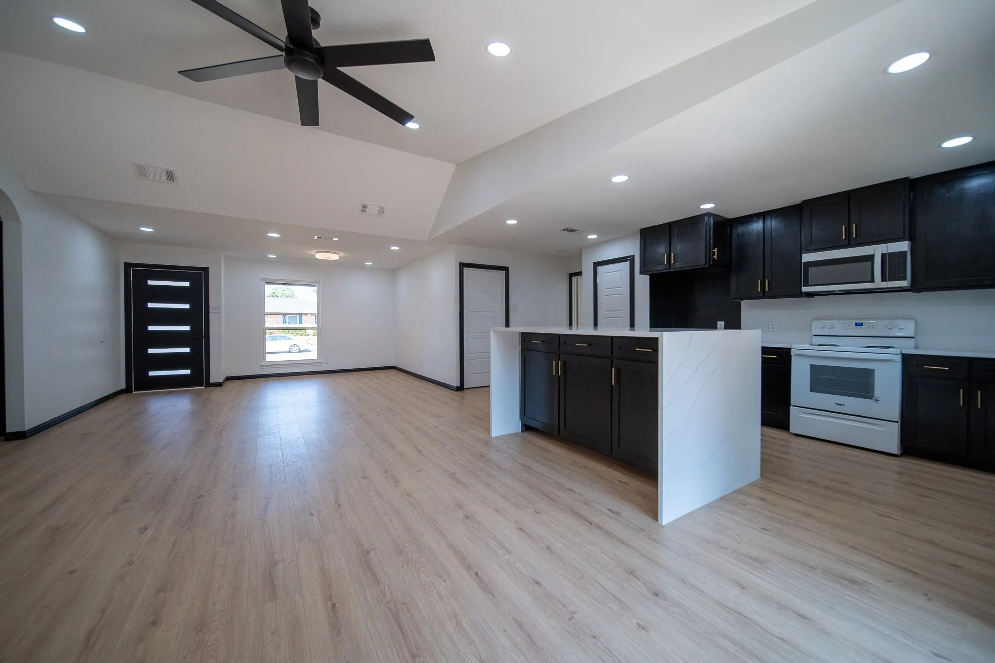 Open-concept living area featuring wood-finish flooring, recessed lighting, and a modern ceiling fan