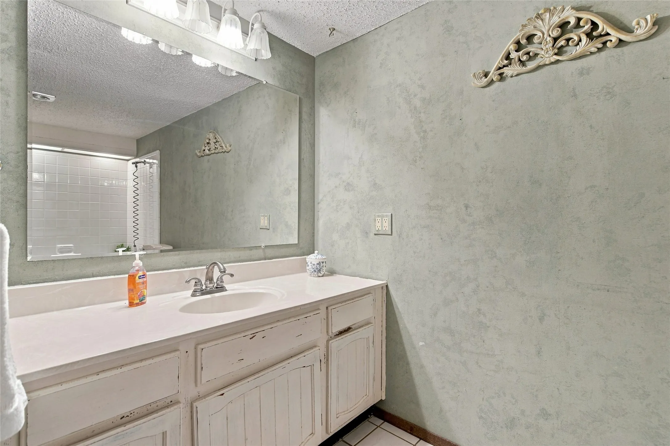 Vanity with integrated sink, wall-mounted mirror, and overhead vanity lighting