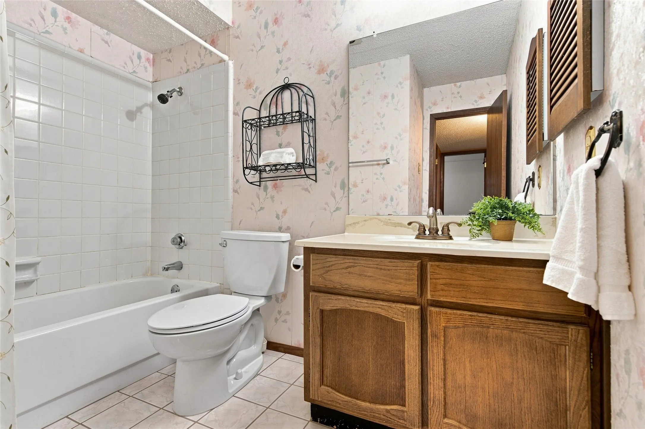 Bathroom featuring a full-size bathtub with white tile surround, a built-in wood-finish vanity with countertop, and a wall-mounted mirror