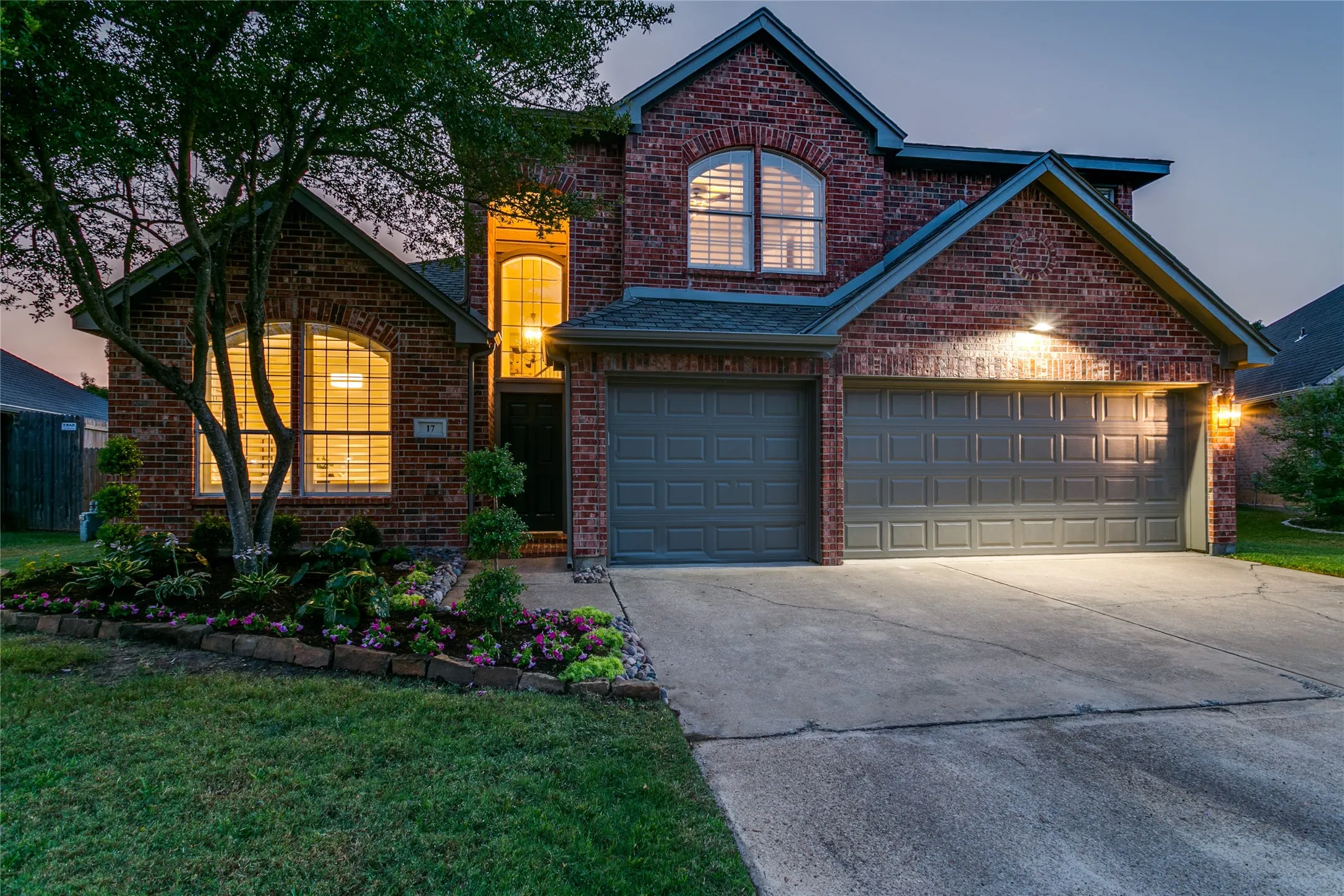 Traditional brick exterior with arched windows, a three-car garage, and update fresh landscaping
