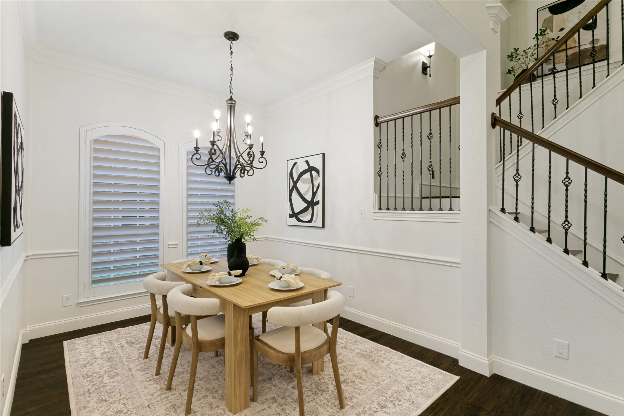 Dark wood-finish flooring with a decorative area rug, complemented by decorative wainscoting and crown molding