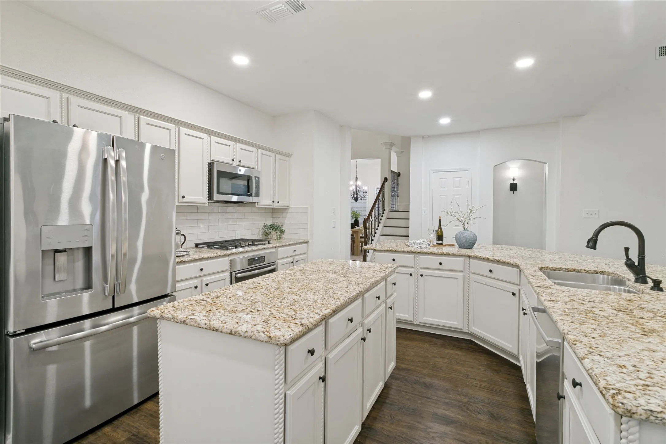 Kitchen featuring white cabinetry, stainless steel appliances, granite countertops, a center island, and wood-finish flooring