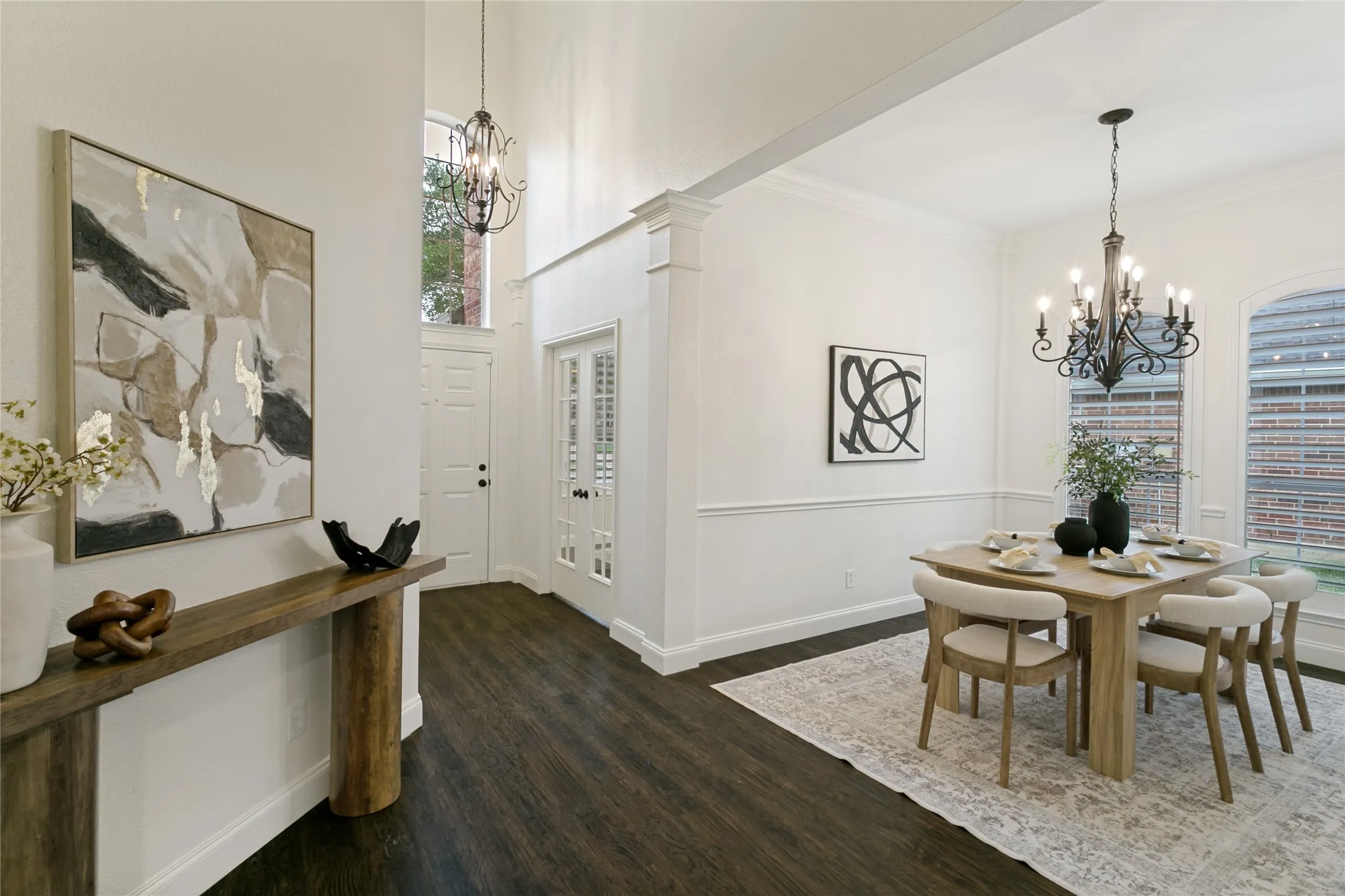 Soaring ceilings with decorative chandelier. This view is lookin back at  front foyer capturing view of dining and office doors.