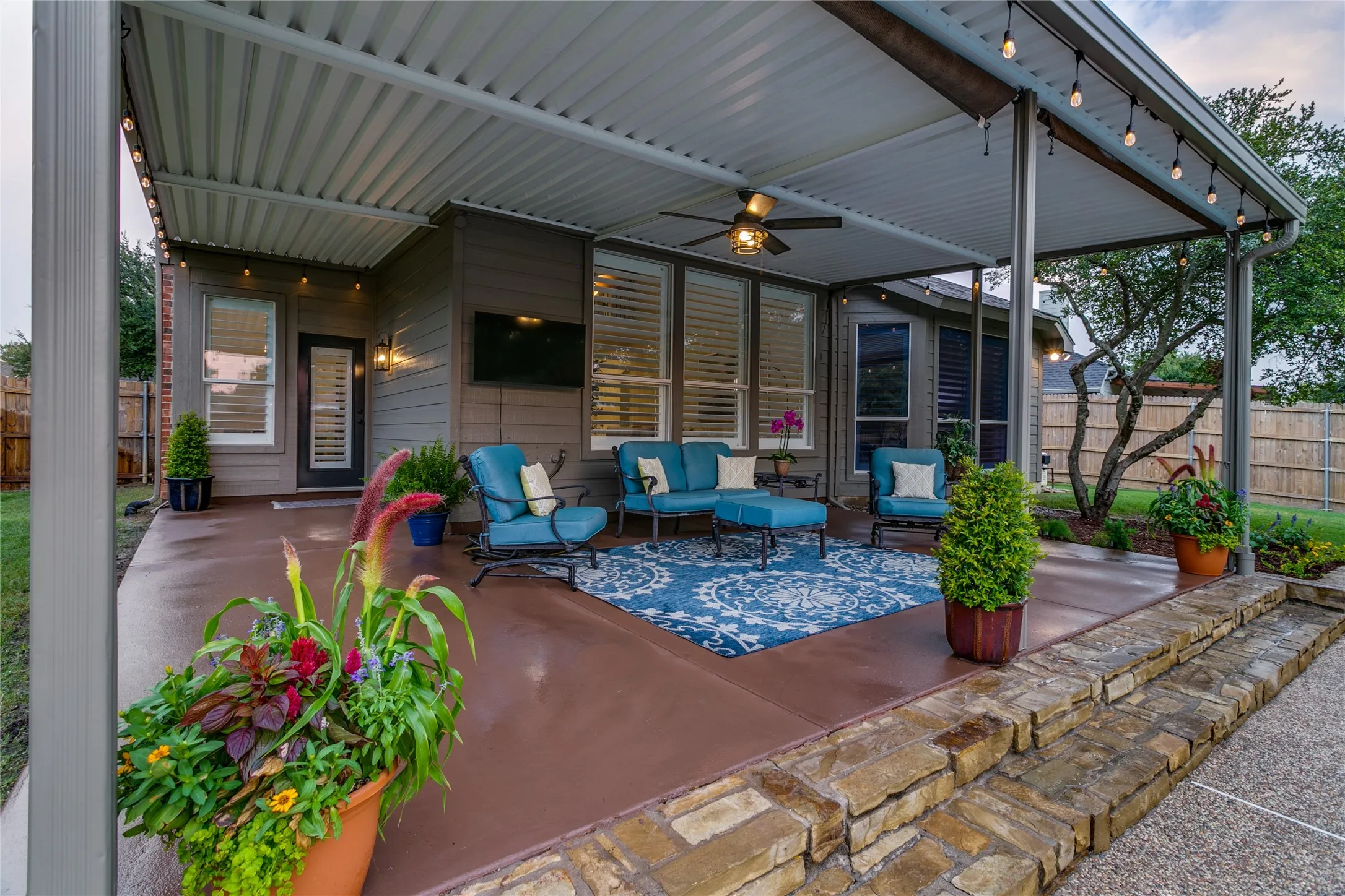 Covered patio with integrated ceiling fan, string lighting and stained concrete.