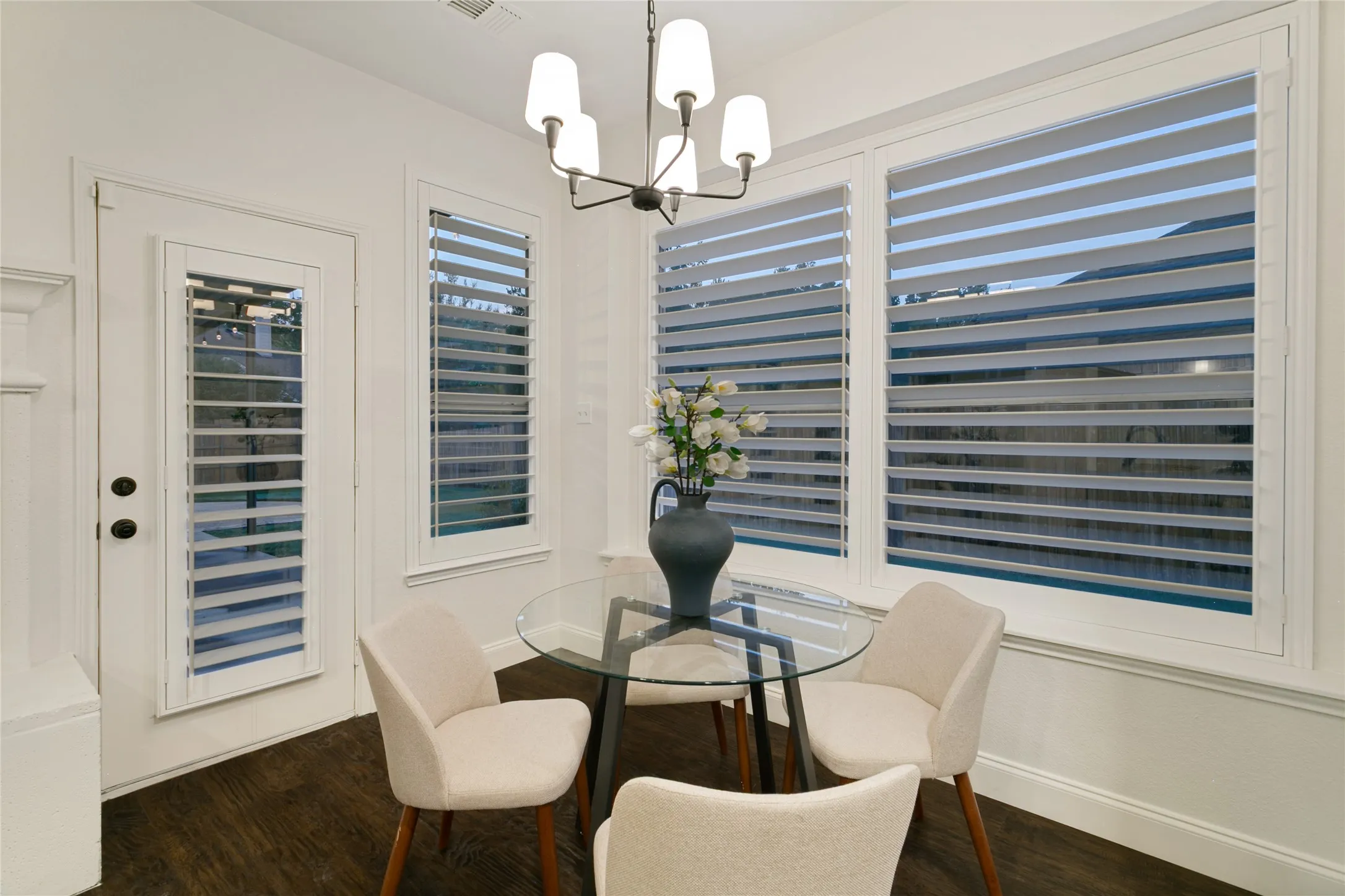 Dark wood-finish flooring with white baseboards, decorative alabaster chandlier