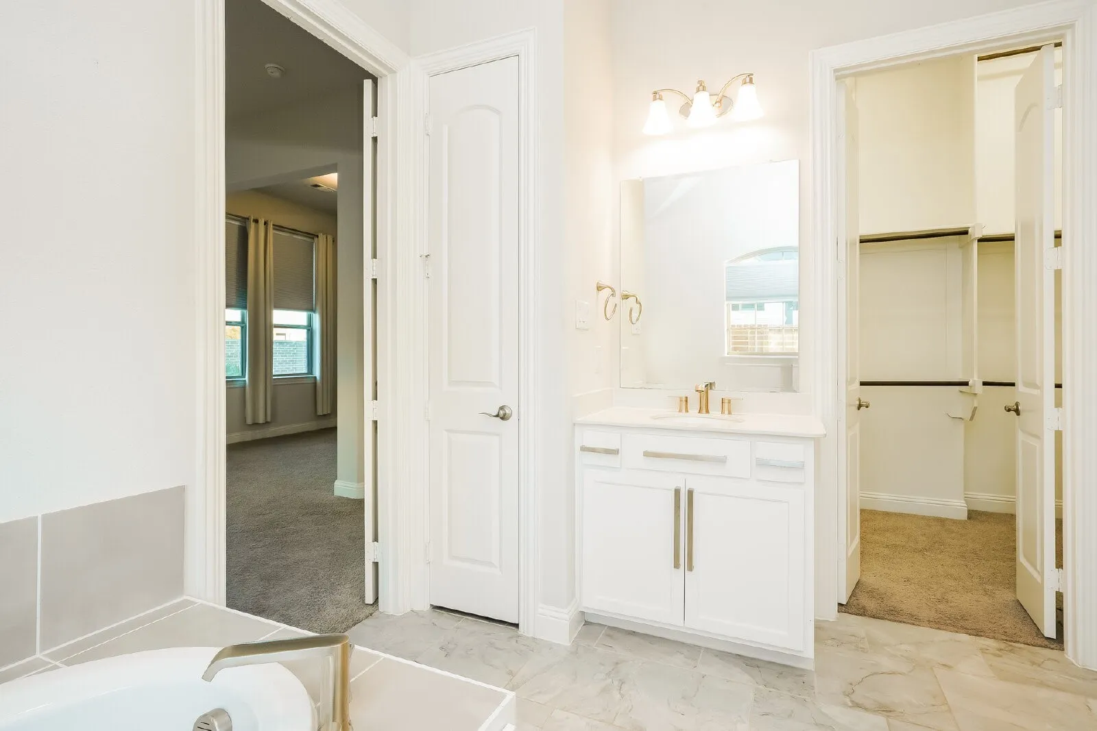 Vanity with integrated sink, white cabinetry, and brushed gold fixtures