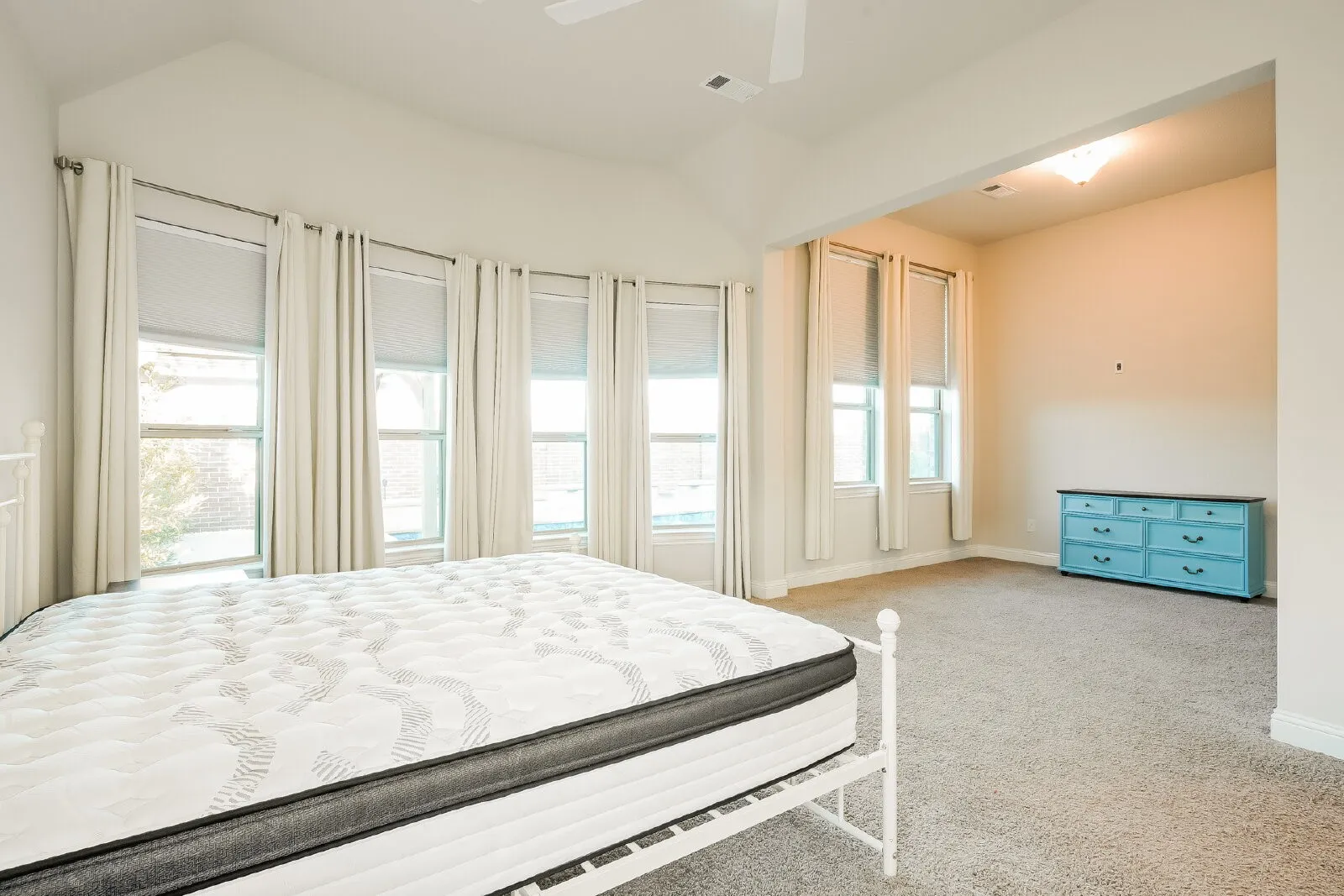 Carpeted room with a vaulted ceiling and a ceiling fan