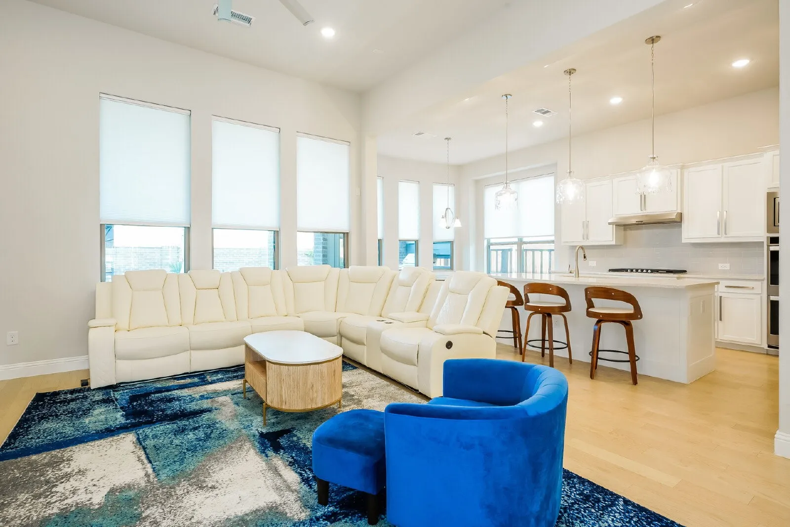 Open-concept living area featuring high ceilings, wood-finish flooring, recessed lighting, and a kitchen island with pendant lighting