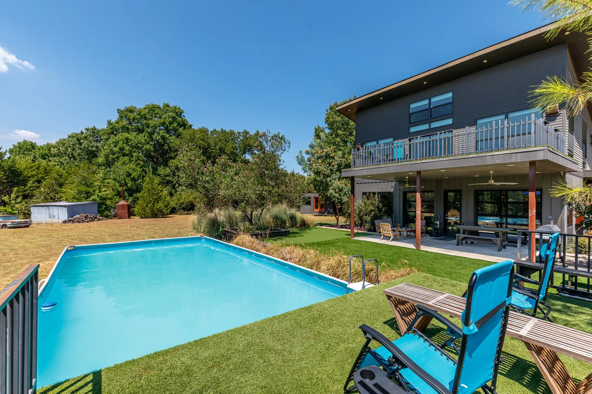 Contemporary exterior with a rectangular pool, covered patio, upper balcony, and a flat roofline