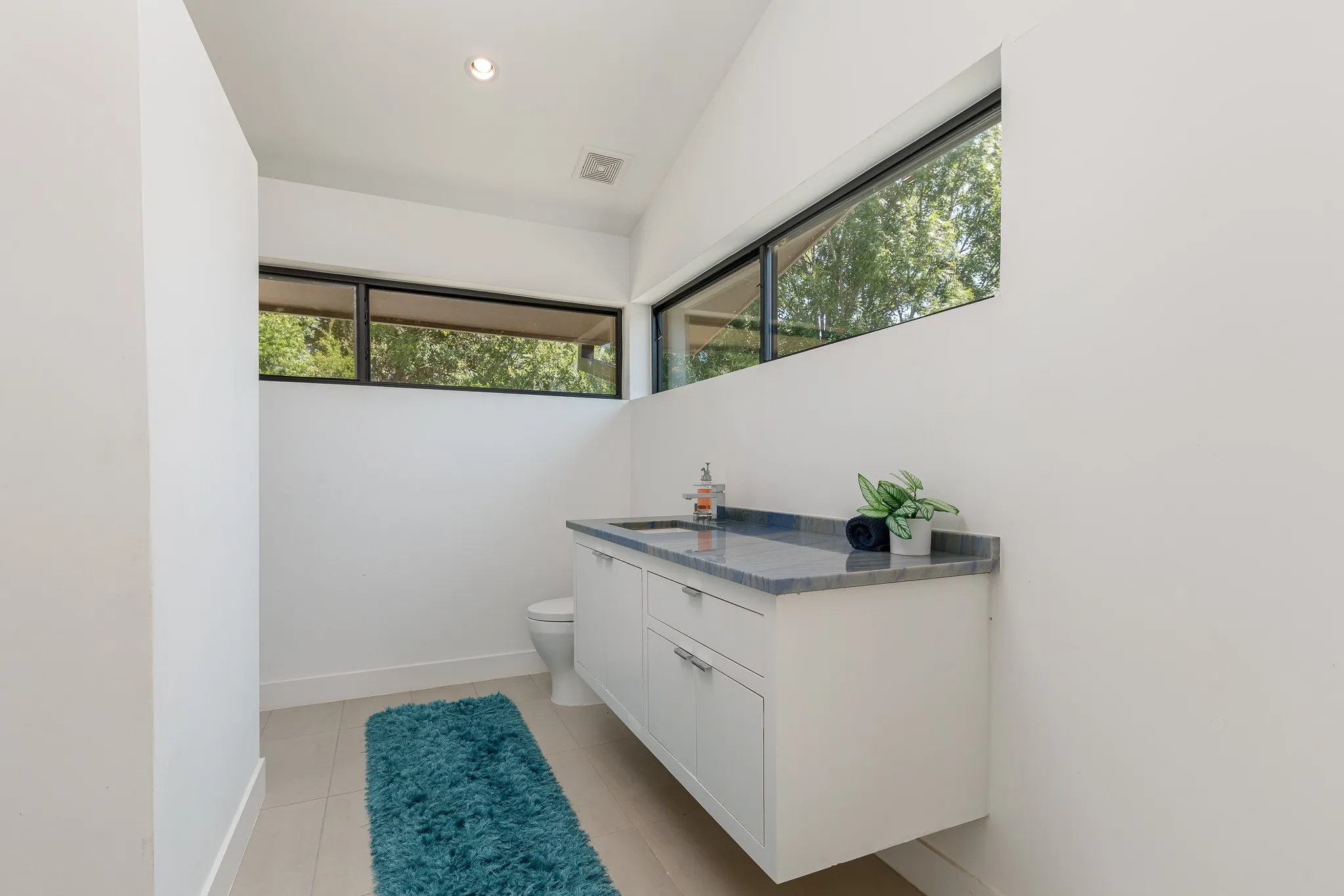 Floating vanity with a built-in sink, stone countertop, and white cabinetry