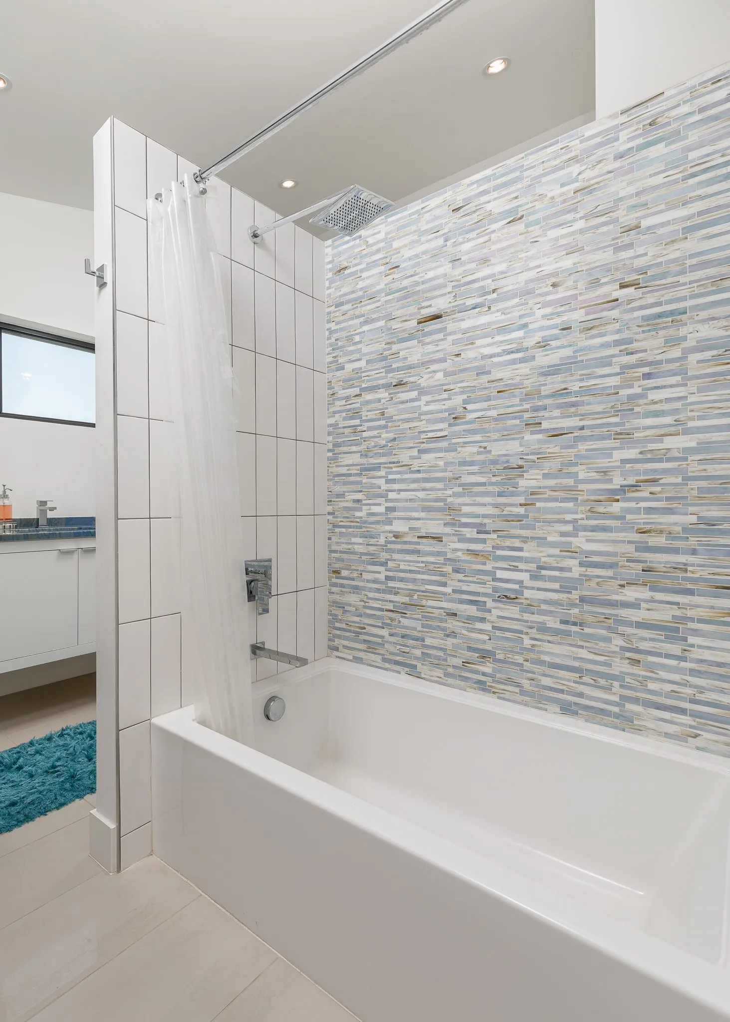White drop-in bathtub with a mosaic tile shower surround