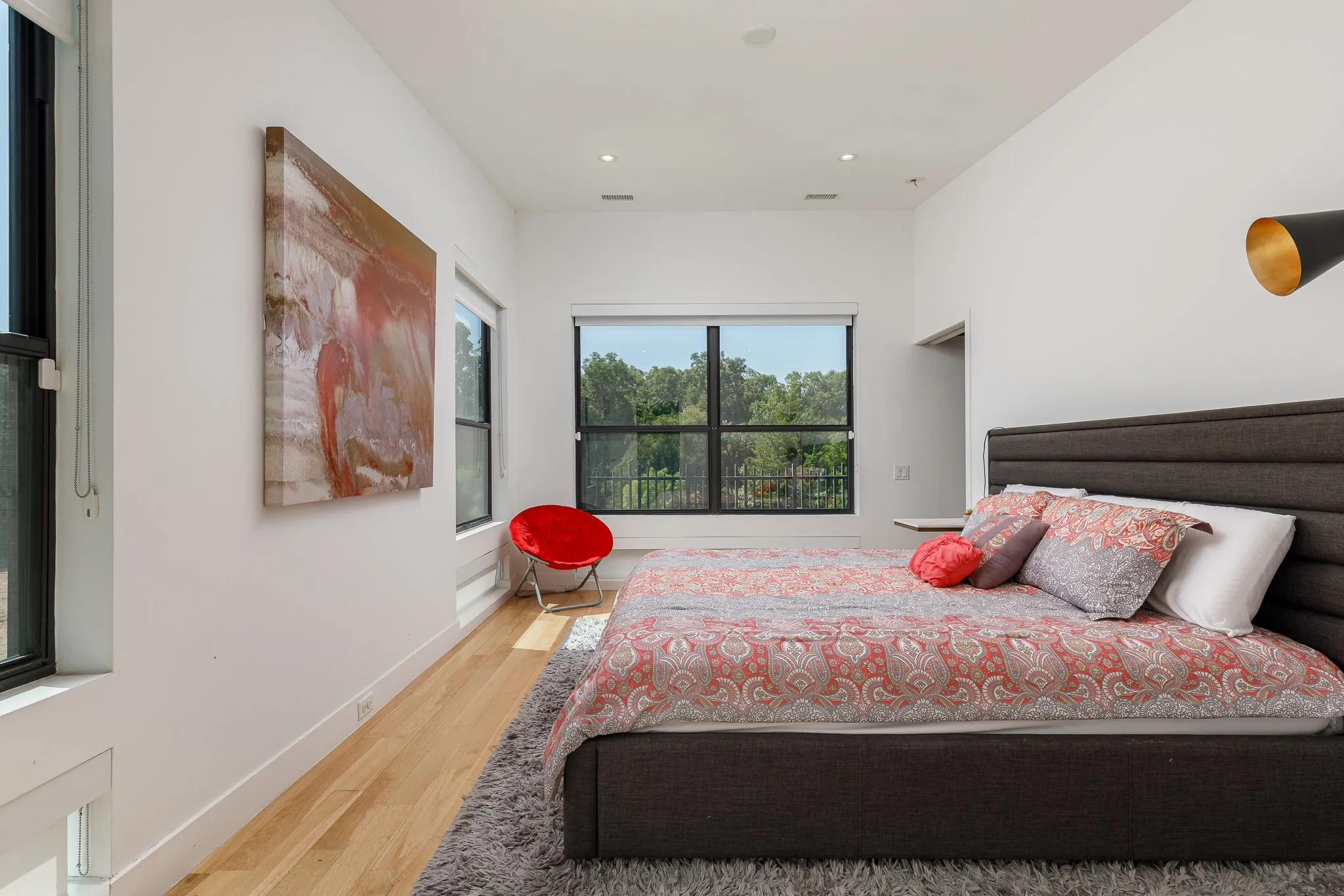 Recessed lighting, wood-finish flooring, multiple windows, and a dark upholstered headboard