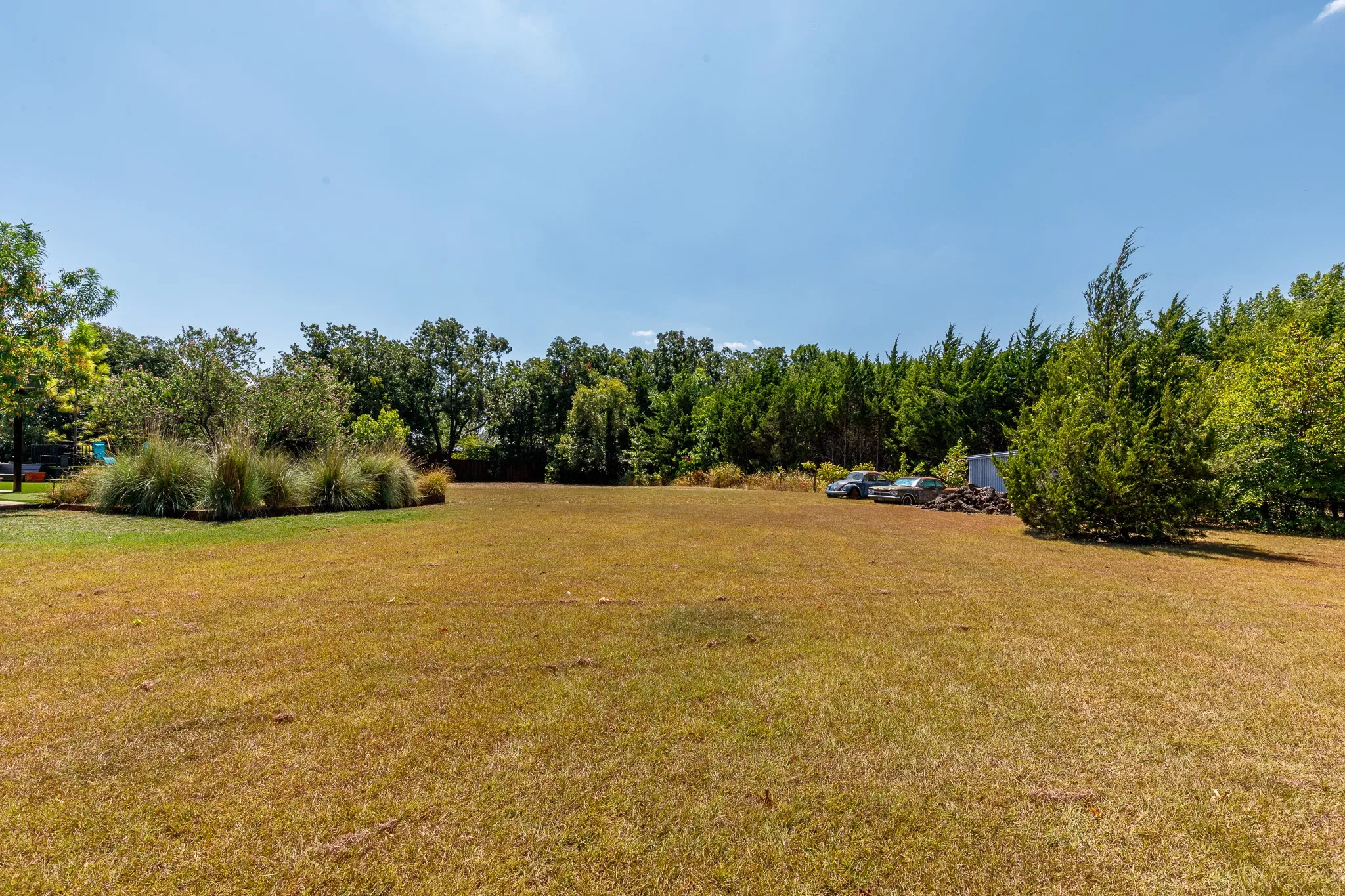 Expansive outdoor space featuring a large grassy area, mature trees, and natural landscaping