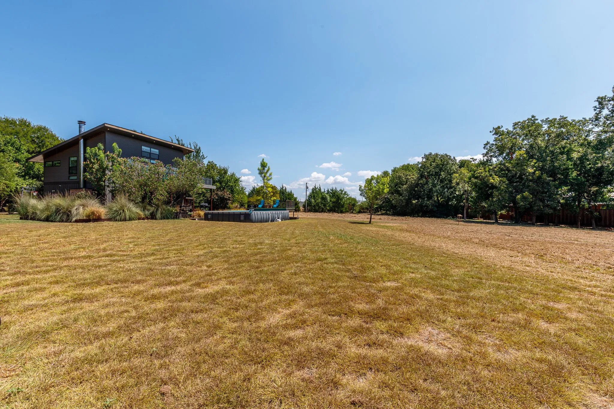 Expansive lawn area with mature trees and perimeter fencing