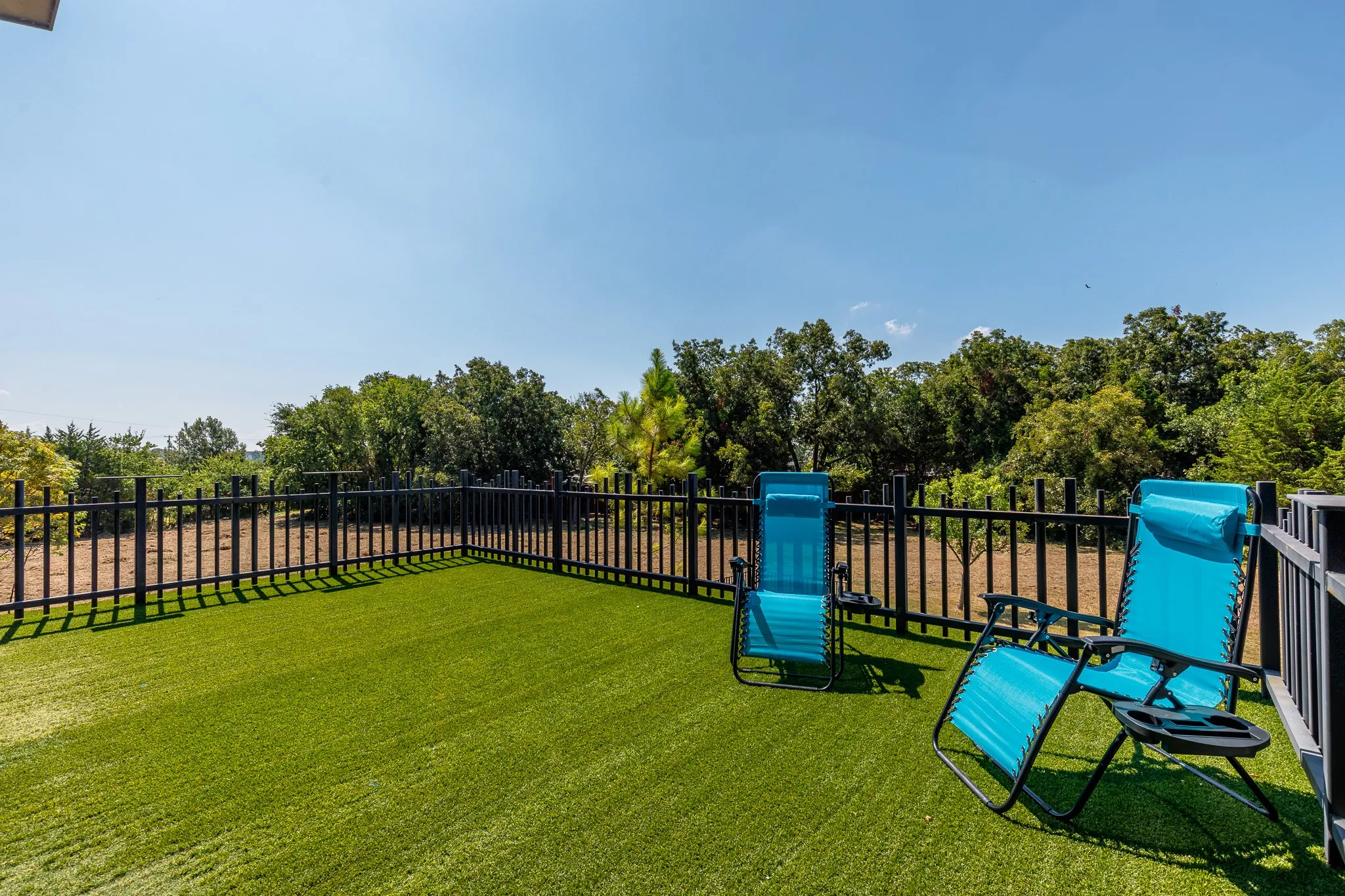 Outdoor deck with artificial turf and black metal fencing