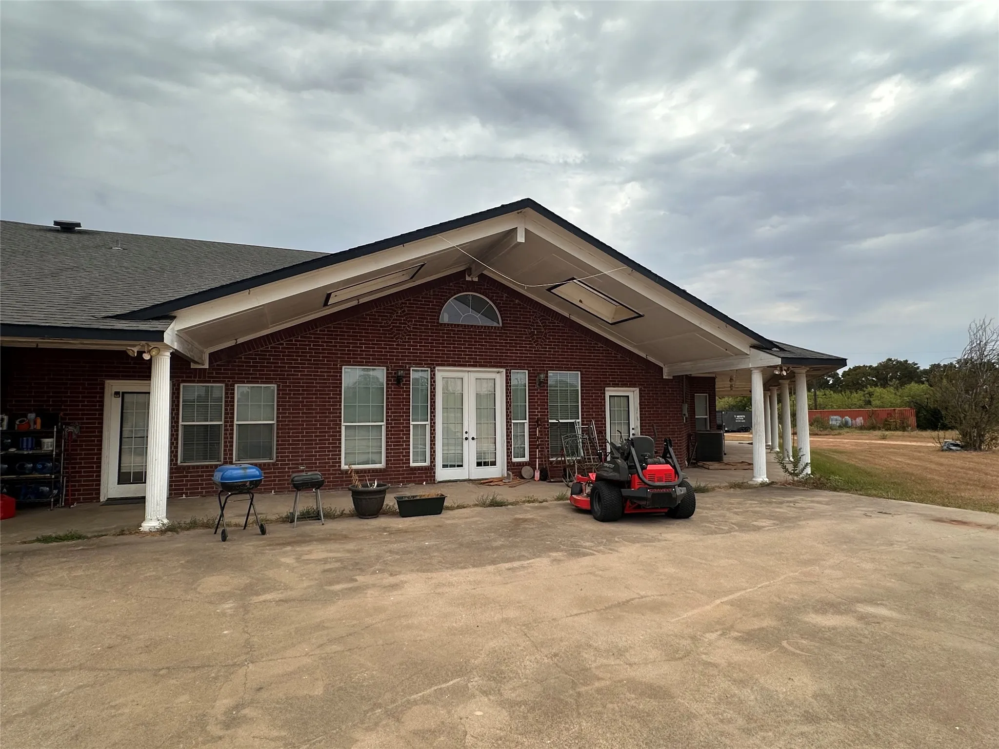 Brick exterior with a covered patio, featuring a gabled roofline and support columns